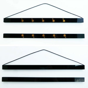 May include: Three black magnetic hanging picture frames with gold floral designs. The frames are hanging from a black string.