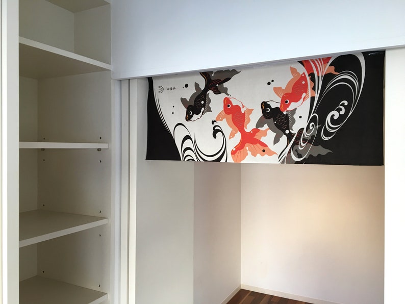 May include: A white closet with a sliding door. The door is open and reveals a black and white fabric panel with a design of red and black fish. The fabric panel is hanging from the top of the closet door.