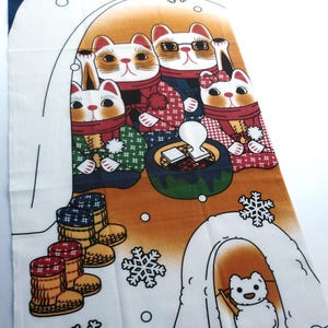 May include: A rectangular fabric wall hanging featuring a winter scene with four illustrated cats wearing scarves and winter clothing, gathered around a small table. A small white dog sits inside an igloo, with snowflakes and boots printed.