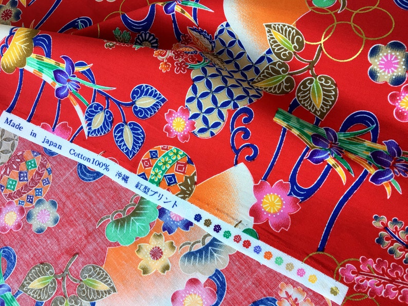 May include: Red cotton fabric with a Japanese-inspired print featuring flowers, leaves, and geometric patterns. The fabric has a label that reads "Made in Japan Cotton 100% 神様 紅型プリント".