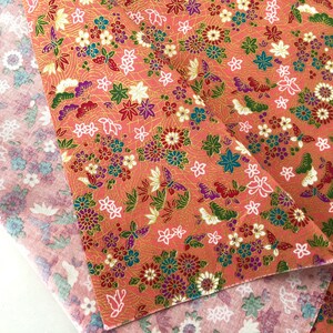 May include: Two pieces of fabric with a floral pattern. The top fabric is pink with a white floral pattern. The bottom fabric is peach with a gold, white, and pink floral pattern.
