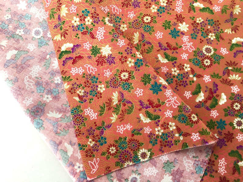 May include: Two pieces of fabric with a floral pattern. The top fabric is pink with a white floral pattern. The bottom fabric is peach with a gold, white, and pink floral pattern.