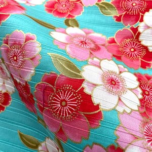 May include: A turquoise fabric with a repeating pattern of pink, red, and white flowers with gold accents. The fabric has a subtle ribbed texture.
