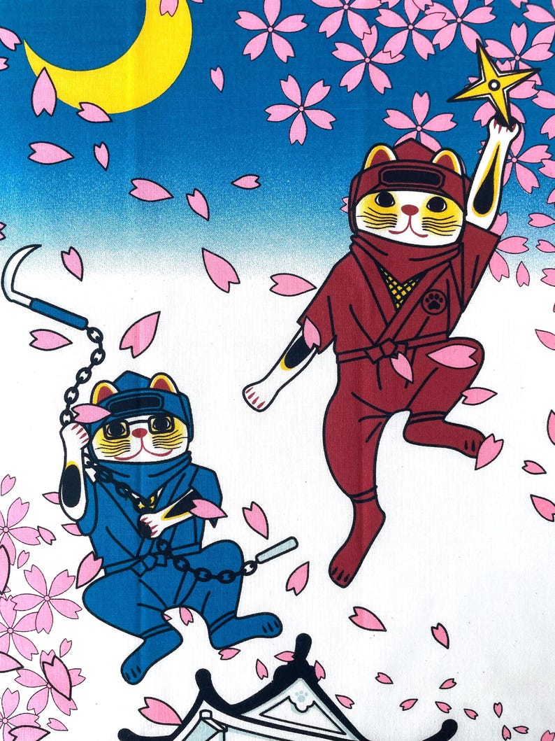 May include: A fabric print featuring two cats dressed as ninjas against a blue sky with a yellow crescent moon and falling pink cherry blossoms. One cat wears a red suit and holds a yellow shuriken, while the other wears blue and holds a kusarigama.