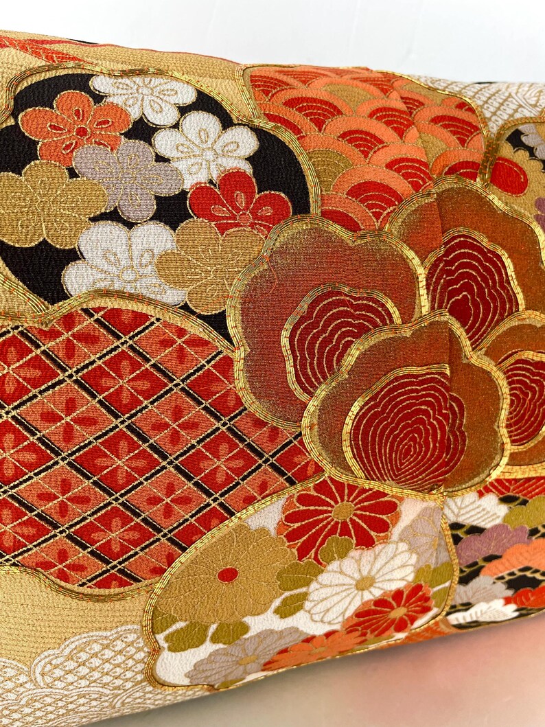 Pode incluir: Uma almofada decorativa com um design de inspira&ccedil;&atilde;o japonesa que apresenta uma variedade de padr&otilde;es florais em tons de vermelho, dourado e branco. A almofada &eacute; feita de um tecido macio e luxuoso e adicionaria um toque de eleg&acirc;ncia a qualquer c&ocirc;modo.