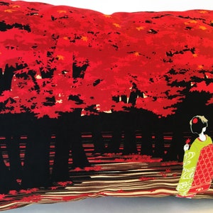 May include: A decorative pillow with a red and black design featuring a Japanese woman in a green and red kimono standing in front of a forest of red maple trees.