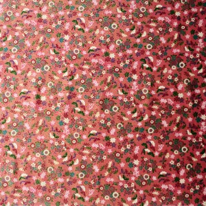 May include: A red fabric with a repeating pattern of small white, pink, and green flowers. The fabric has a subtle shimmer.