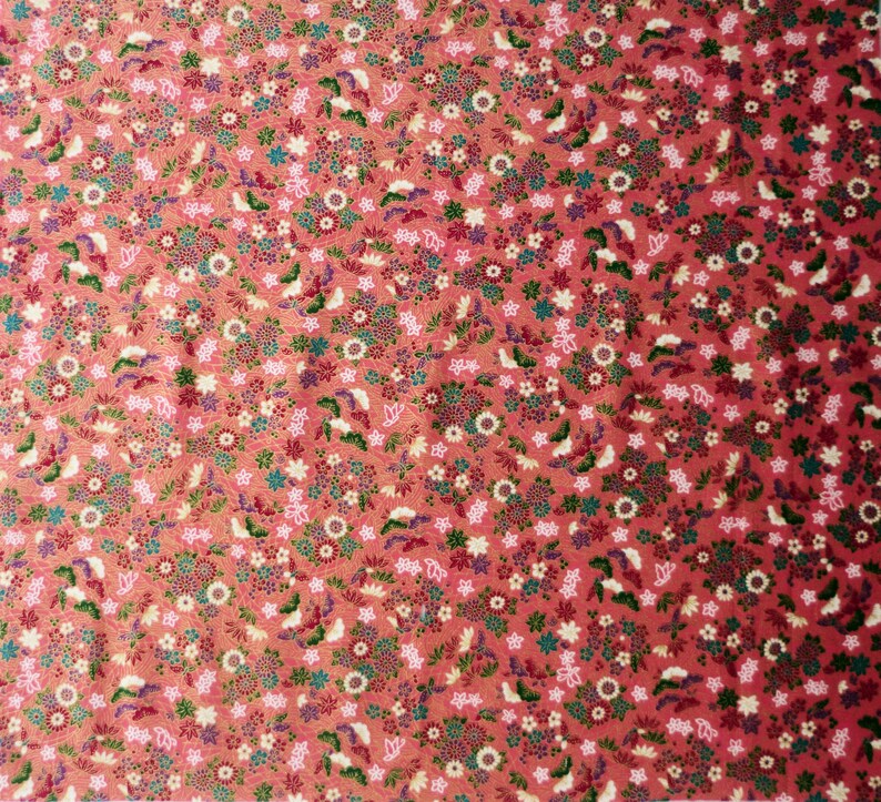May include: A red fabric with a repeating pattern of small white, pink, and green flowers. The fabric has a subtle shimmer.