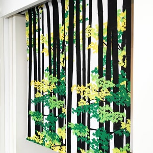 May include: Black and white patterned room divider with a design of trees and leaves in shades of green and yellow. The divider is made of fabric and hangs from a track.
