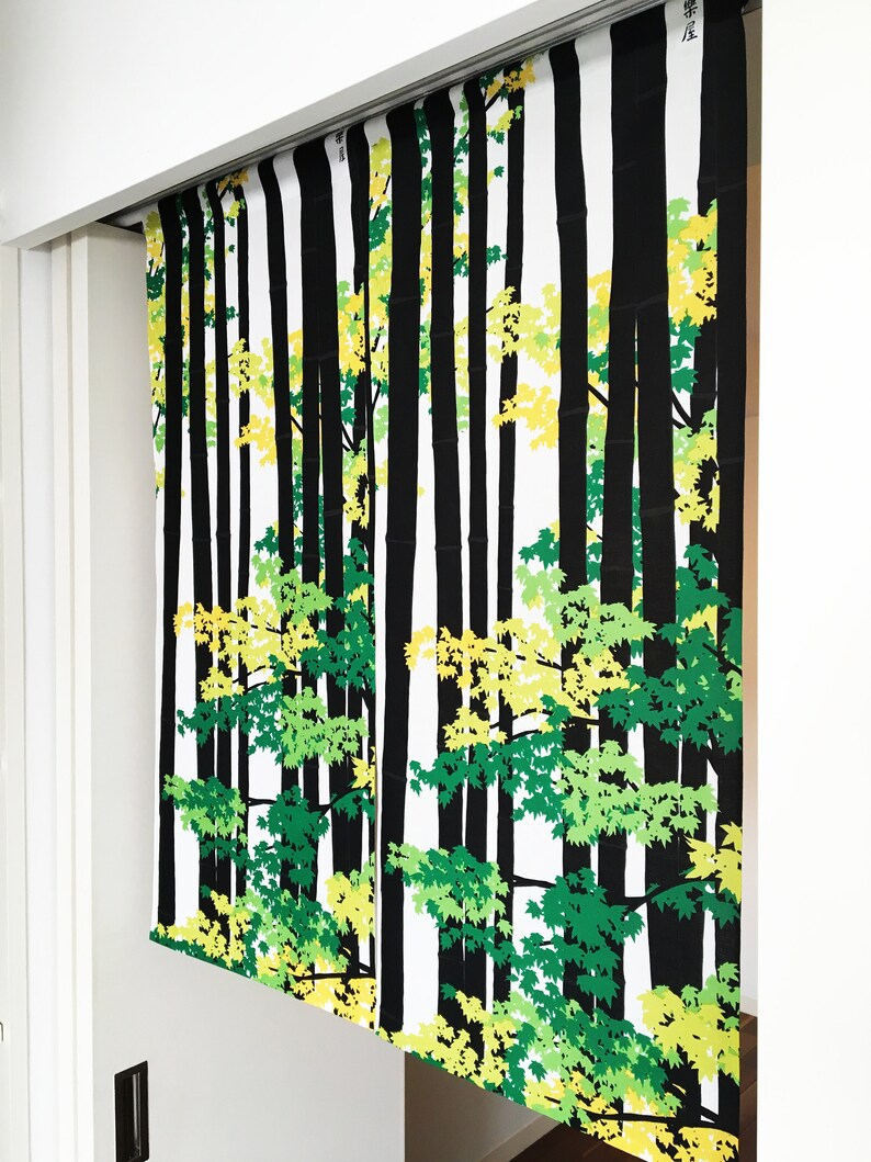 May include: Black and white patterned room divider with a design of trees and leaves in shades of green and yellow. The divider is made of fabric and hangs from a track.