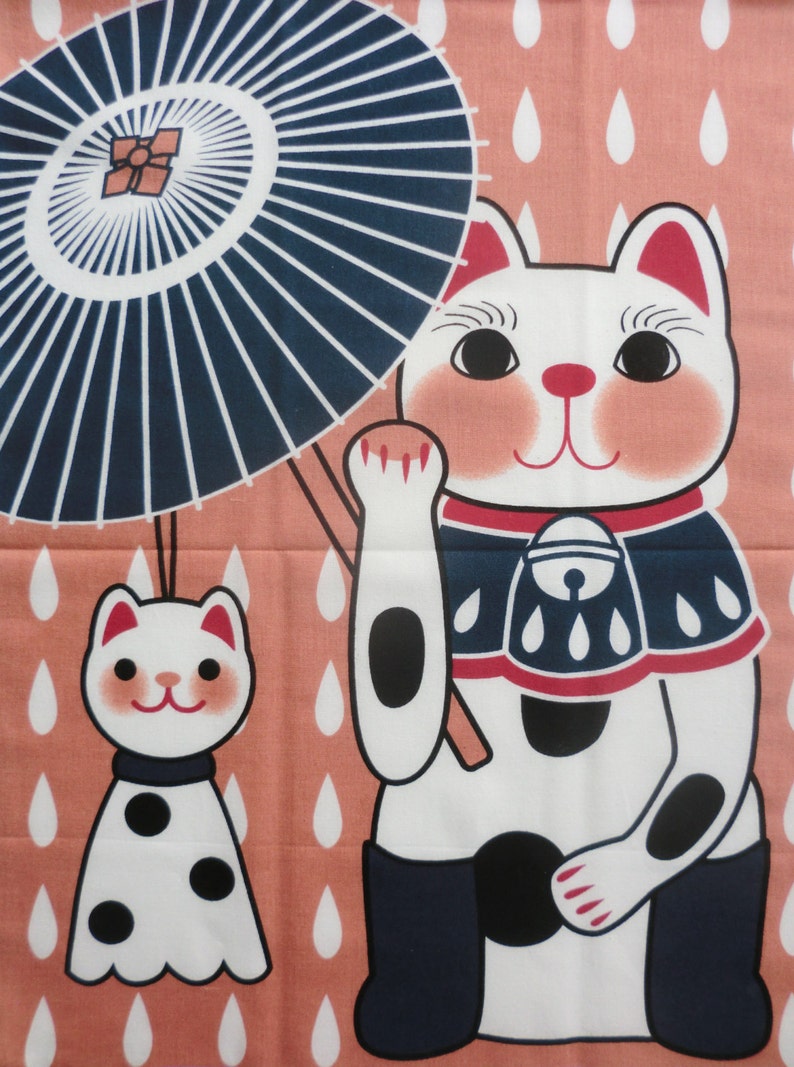 May include: A pink fabric panel with a white cat holding a blue and white umbrella. The cat is wearing a blue and red bib with white spots. The background is a pink fabric with white raindrops.