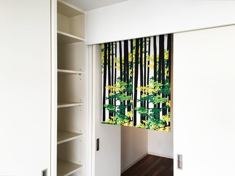 May include: White closet doors with a black and white patterned curtain with green and yellow leaves hanging in the doorway. The curtain is made of fabric and has a simple design.