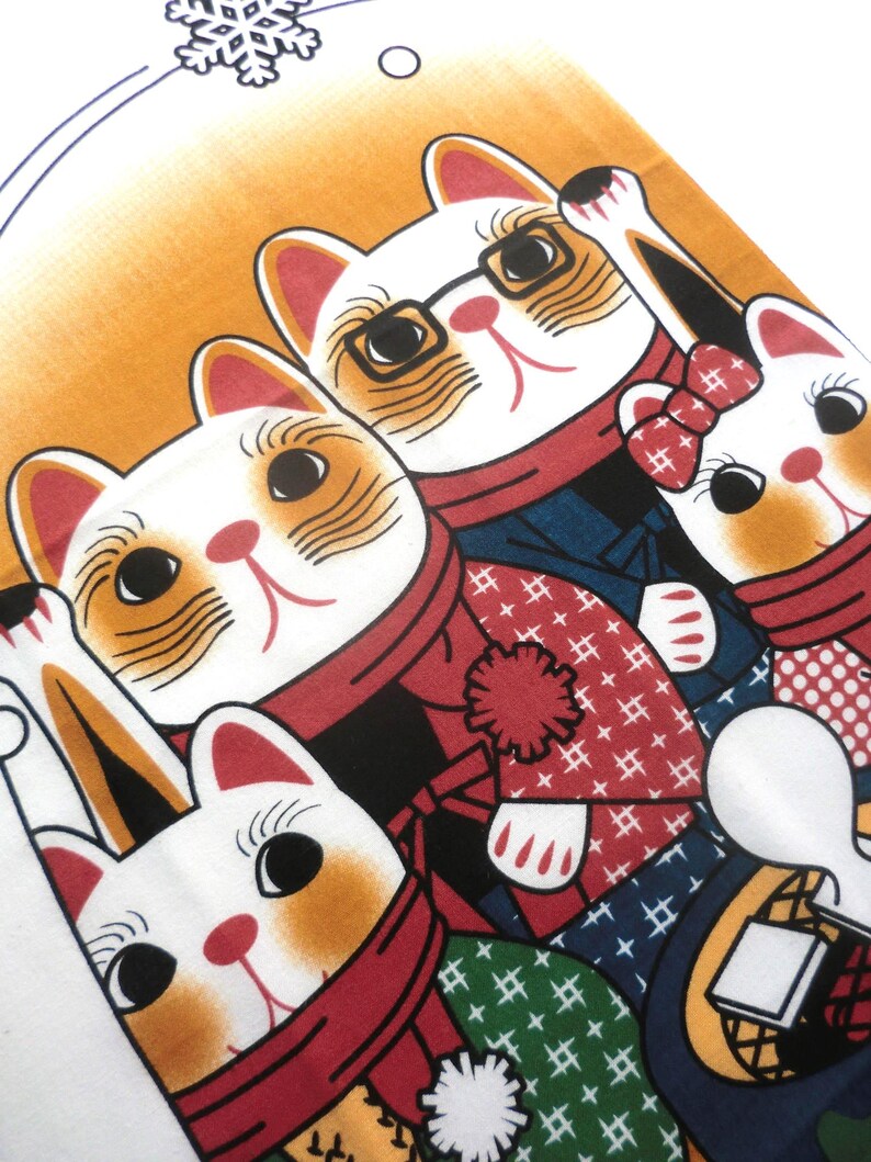 May include: A fabric print featuring four stylized white cats with orange markings, wearing red scarves and patterned winter clothing. One cat wears black-rimmed glasses, another has a red bow, and a snowflake icon is visible at the top.