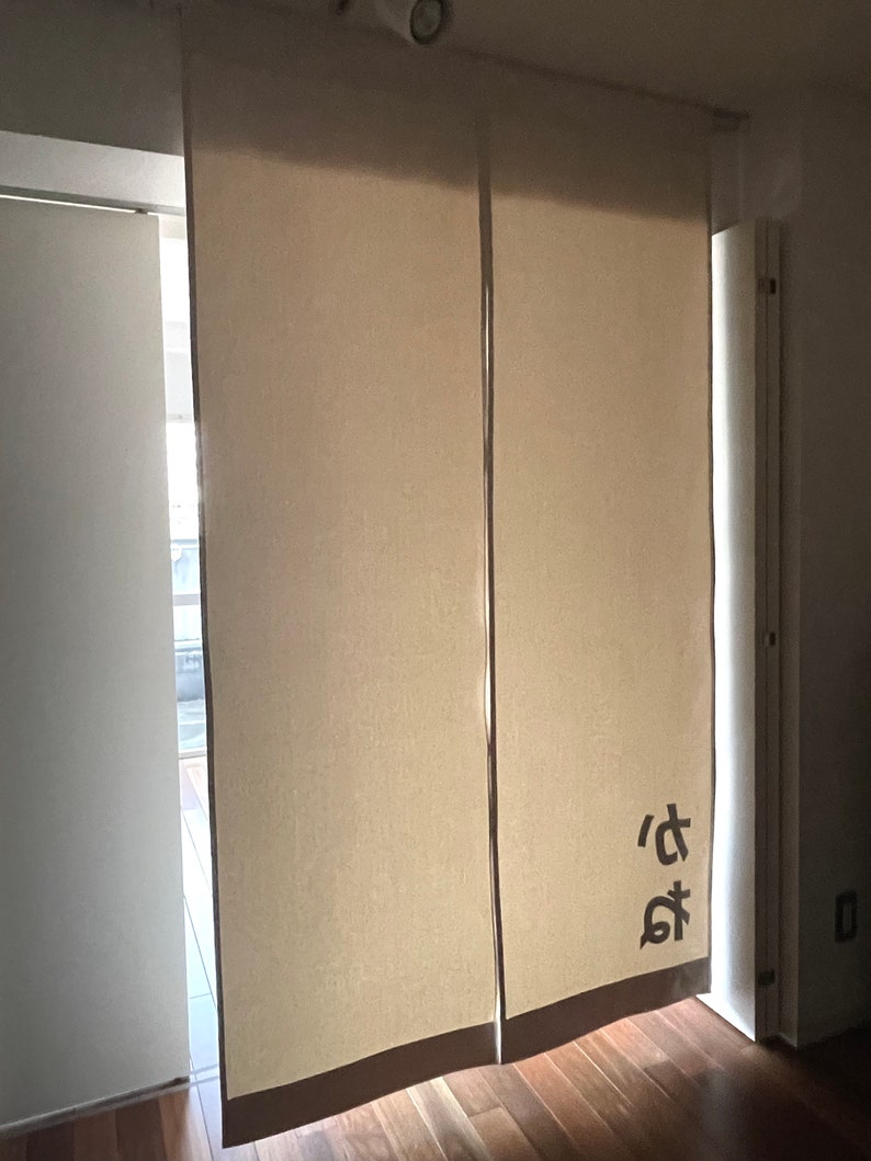 Puede incluir: Dos separadores de ambientes de tela beige con un car&aacute;cter japon&eacute;s impreso en el panel derecho.