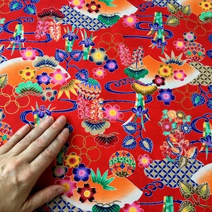 May include: Red fabric with a repeating pattern of colorful flowers, leaves, and geometric shapes. The fabric has a traditional Japanese design.