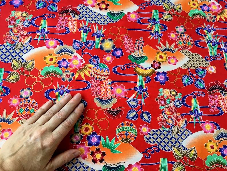May include: Red fabric with a repeating pattern of colorful flowers, leaves, and geometric shapes. The fabric has a traditional Japanese design.