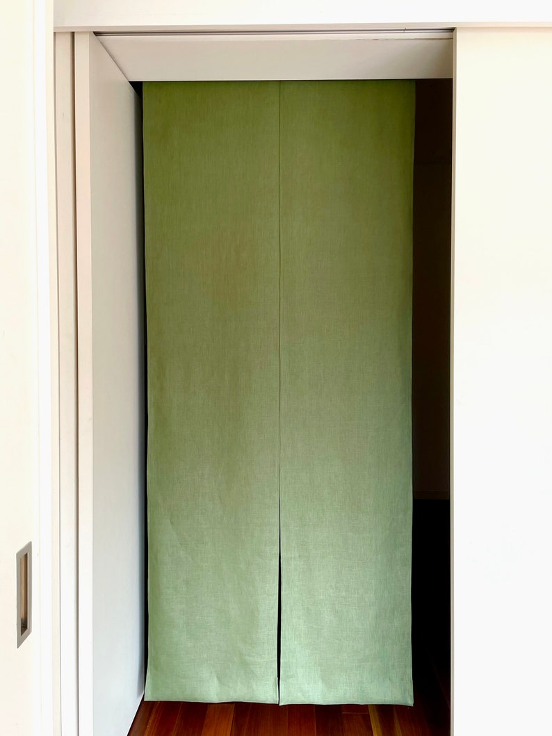 Puede incluir: Un par de divisores de habitaci&oacute;n de tela verde colgados en una puerta. Los divisores est&aacute;n hechos de una tela texturizada y tienen un brillo sutil.