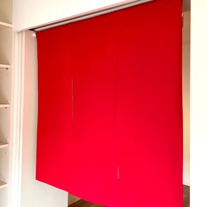May include: Three red fabric panels hanging from a track system, creating a room divider. The panels are made of a smooth, solid fabric.