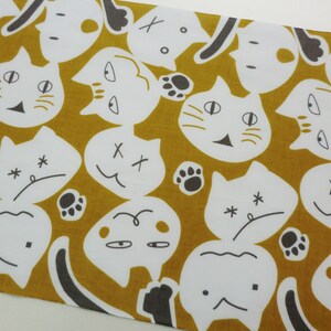 May include: A mustard yellow fabric with a repeating pattern of white cats with different facial expressions. The cats have black eyes, noses, and whiskers. Some cats have X's for eyes, while others have closed eyes. Some cats have paw prints on their heads.