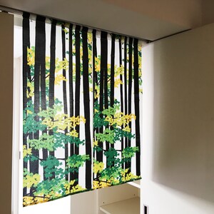 May include: White sliding closet doors with a black and green patterned curtain featuring a forest scene with trees and leaves.