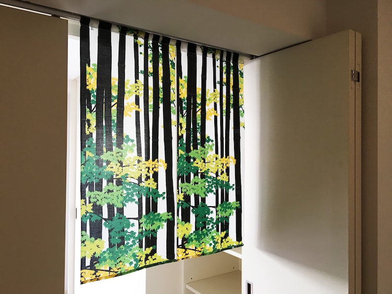 May include: White sliding closet doors with a black and green patterned curtain featuring a forest scene with trees and leaves.