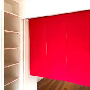 May include: A white closet with open shelves and a red fabric room divider hanging from a track.