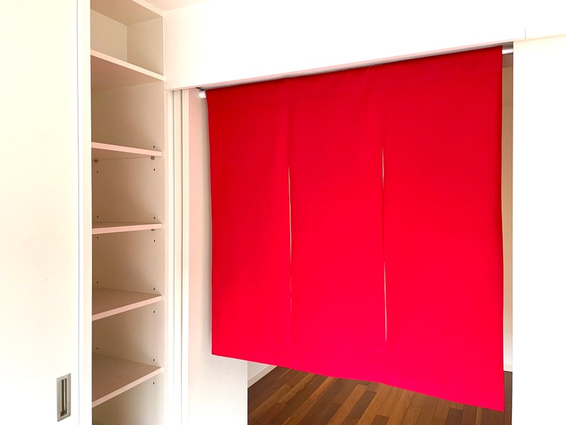 May include: A white closet with open shelves and a red fabric room divider hanging from a track.