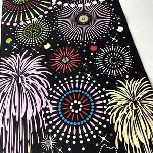 May include: Black fabric with a repeating pattern of colorful fireworks. The fireworks are in various shapes and sizes, with some having a more traditional starburst shape and others having a more modern, abstract design.