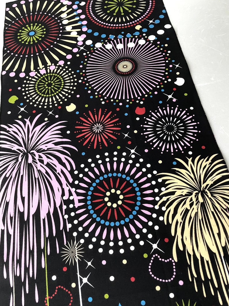 May include: Black fabric with a repeating pattern of colorful fireworks. The fireworks are in various shapes and sizes, with some having a more traditional starburst shape and others having a more modern, abstract design.