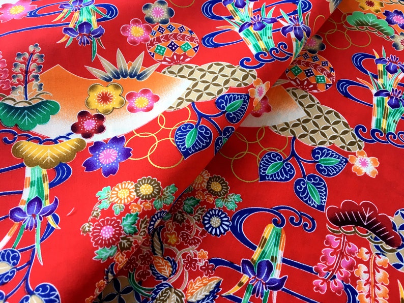 May include: Red fabric with a repeating pattern of colorful flowers, leaves, and geometric shapes. The fabric has a traditional Japanese design.
