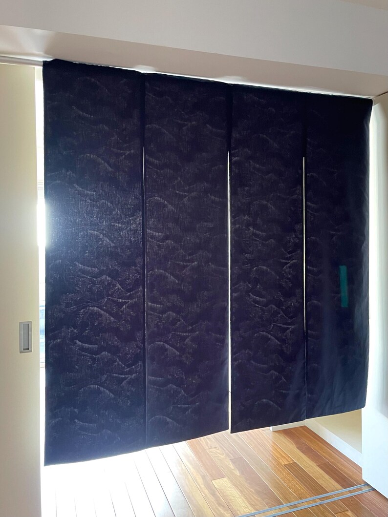 May include: A set of four dark blue fabric panels with a subtle wave pattern. The panels are hanging from a track and are partially open, revealing a wooden floor.