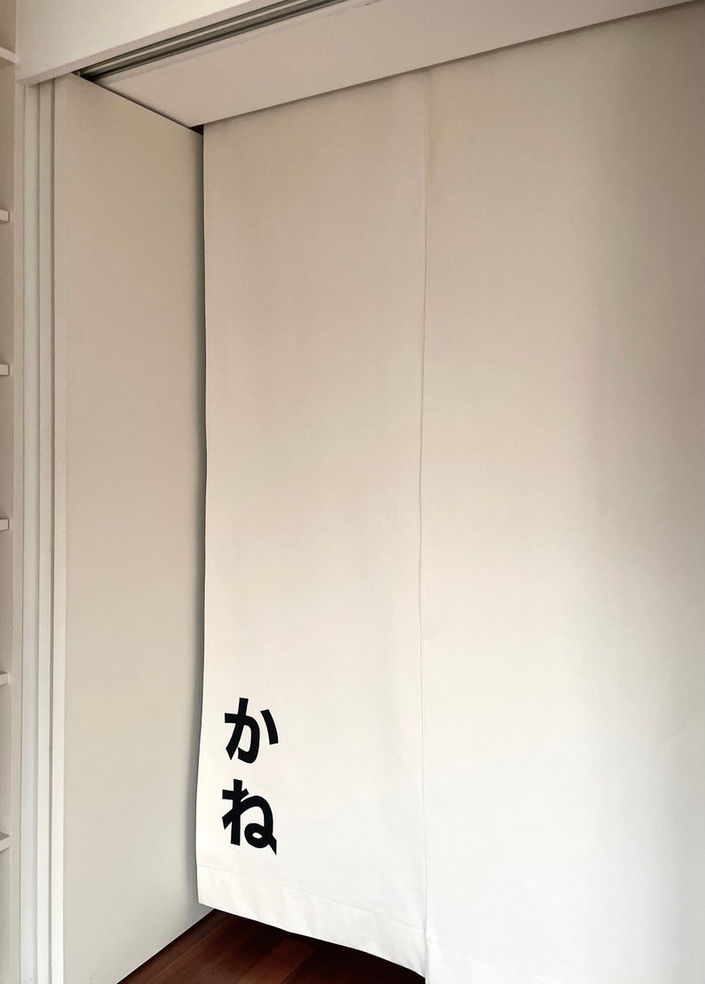 Puede incluir: Puerta corredera blanca con la palabra japonesa "ka" y "ne" escrita en negro en la puerta.