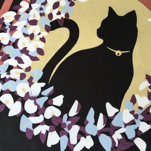 以下が含まれることがあります： 黒猫のシルエットが、金色の首輪をつけて、白と青の花の輪の中に座っています。背景は黒と茶色のストライプです。