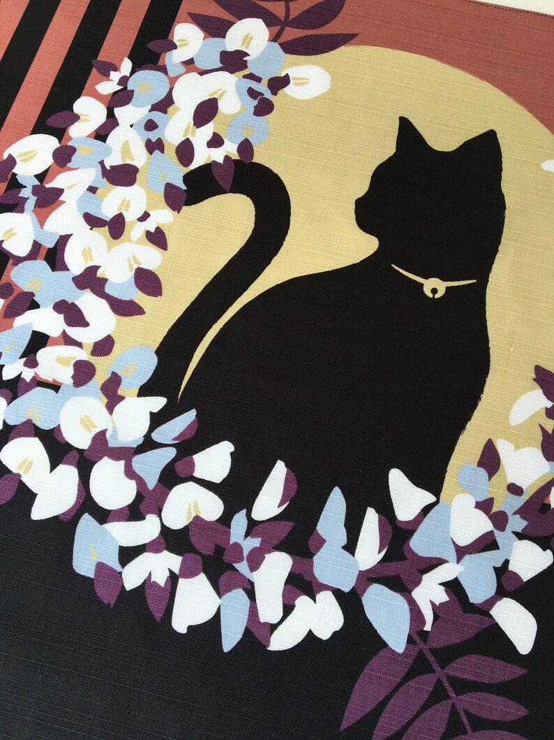 以下が含まれることがあります： 黒猫のシルエットが、金色の首輪をつけて、白と青の花の輪の中に座っています。背景は黒と茶色のストライプです。