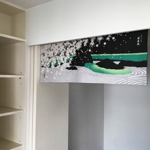 May include: A white, black and green Japanese-style room divider with a cherry blossom and landscape design. The divider has the Japanese text "春風" written on it, which translates to "spring breeze".