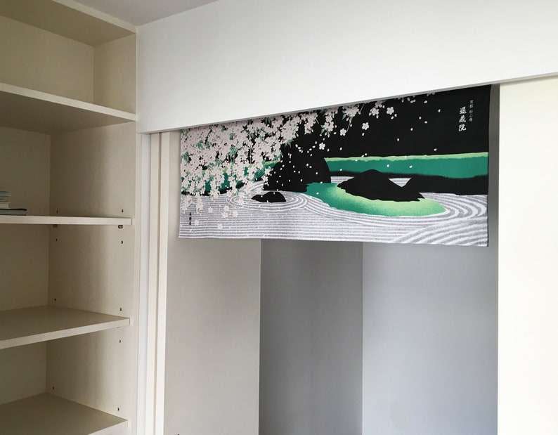 May include: A white, black and green Japanese-style room divider with a cherry blossom and landscape design. The divider has the Japanese text "春風" written on it, which translates to "spring breeze".