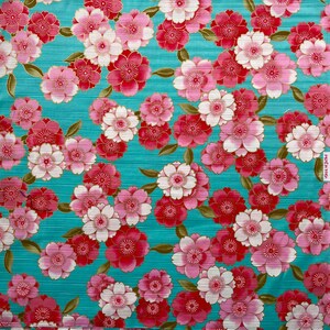 May include: A teal fabric with a repeating pattern of pink and red flowers with gold accents. The flowers have a layered petal design.