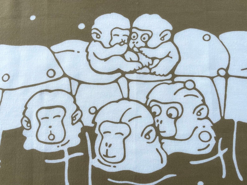 May include: A fabric with a repeating pattern of white cartoon monkeys on a brown background. The monkeys are in various poses, some hugging and others with surprised expressions. The design has a playful and whimsical feel.