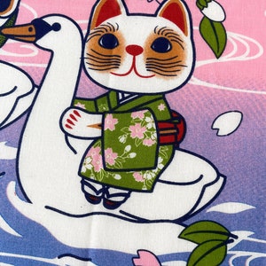 May include: A fabric print featuring a white cat wearing a green floral kimono, riding on the back of a white swan. The background transitions from pink to purple with stylized water ripples and cherry blossom branches with pink flowers.