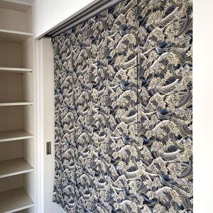 May include: A set of blue and gold curtains with a wave pattern. The curtains are hanging on a track system and are partially open, revealing a white closet behind them.