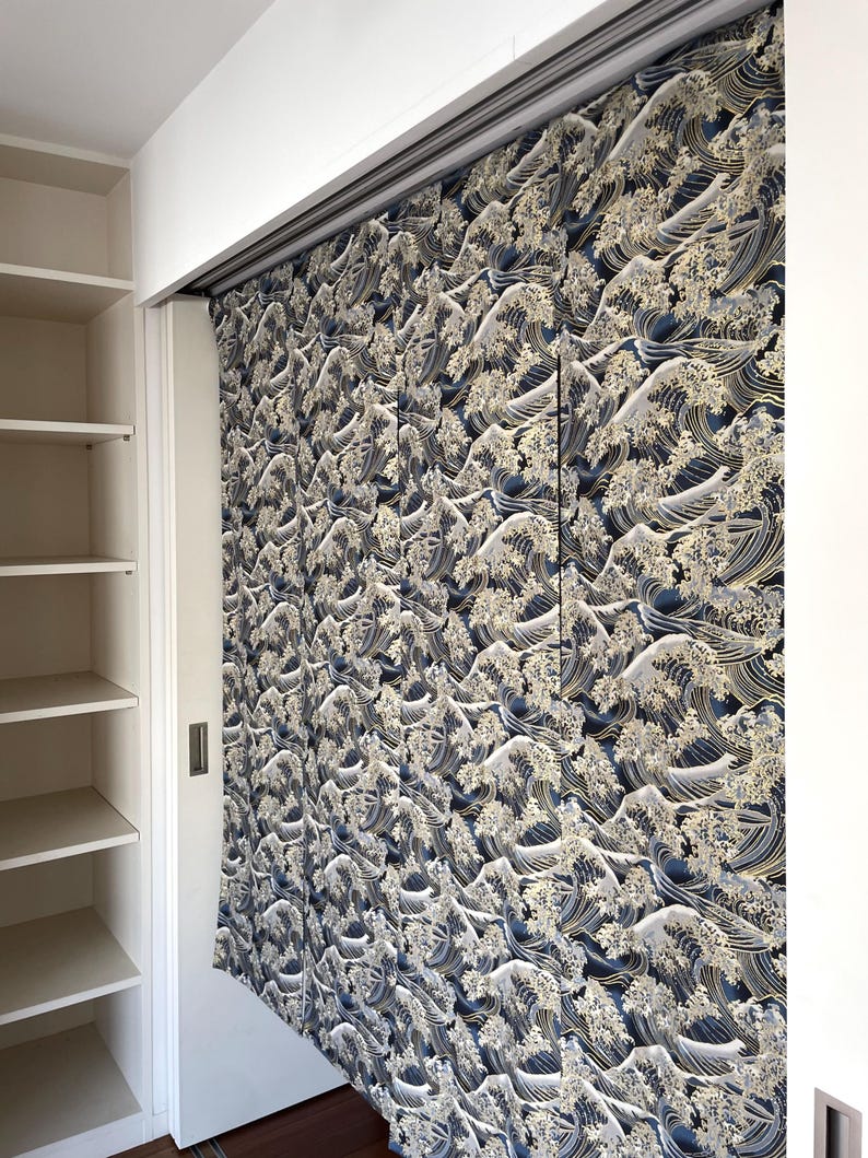 May include: A set of blue and gold curtains with a wave pattern. The curtains are hanging on a track system and are partially open, revealing a white closet behind them.