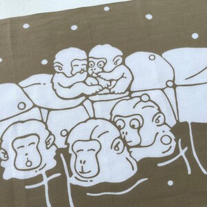 May include: A tan and white textile featuring a repeating pattern of cartoon monkeys. The monkeys are depicted in a simple, line-art style, with some embracing and others with various expressions. White dots are scattered across the tan background.