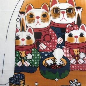 May include: A fabric print featuring four stylized cats wearing scarves and winter clothing. The cats are positioned around a small green brazier with a white stamp. The background is orange with white snowflake patterns and small circular accents.