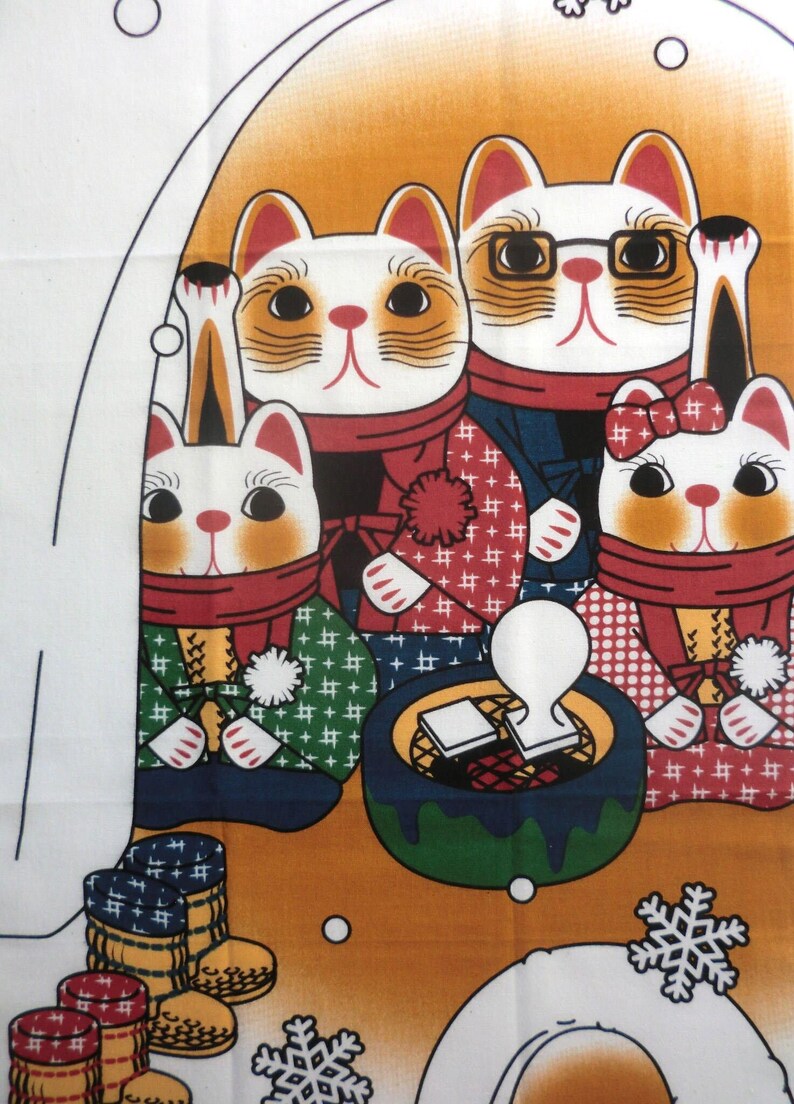 May include: A fabric print featuring four stylized cats wearing scarves and winter clothing. The cats are positioned around a small green brazier with a white stamp. The background is orange with white snowflake patterns and small circular accents.