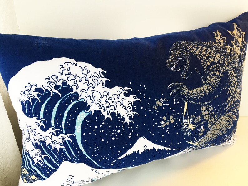 May include: A blue pillow with a white and blue wave design and a Godzilla-like creature in the upper right corner.