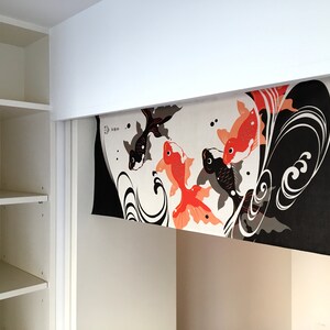 May include: A white, black, and orange fabric panel with a design of stylized waves and goldfish. The panel is hanging from a white ceiling.