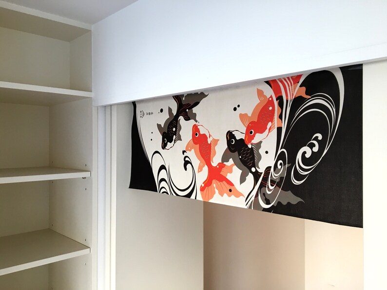 May include: A white, black, and orange fabric panel with a design of stylized waves and goldfish. The panel is hanging from a white ceiling.