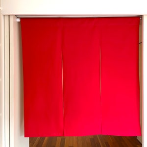 May include: Three panels of red fabric hang from a white rod. The fabric is smooth and has a slight sheen. The panels are evenly spaced and hang straight down.