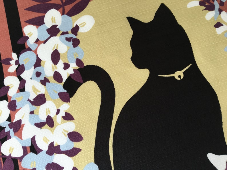 以下が含まれることがあります： 金色の首輪をした黒い猫のシルエットで、尻尾が体の周りに巻き付いている。猫は、白、紫、青の色合いの花柄の黄色い背景の上にいる。