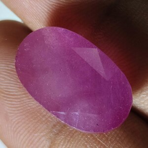 Op de afbeelding: Een ovaalvormige, gefacetteerde edelsteen met een levendige magenta-roze tint. De steen heeft een glad, gepolijst oppervlak met zichtbare geometrische facetten die het licht vangen, wat een doorschijnende kwaliteit en een consistente, dieproze kleur laat zien.